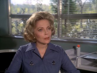 Barbara is sitting in a hospital bedroom on Earth; there is a sunny garden outside the window. She has full flashback hair, and appears to be looking at someone off camera with a mixture of incredulity and contempt.