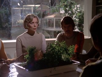 Barbara sits at the table in Alpha's hydroponics bay with the senior staff; they are all holding hands in a spirit circle. She seems to be giving Paul some serious side eye.