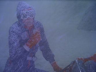 On a terrifyingly cold and bleak ice planet, Barbara, wearing an environmental suit and snow goggles and covered in foam, lies down in the snow to get some rest.